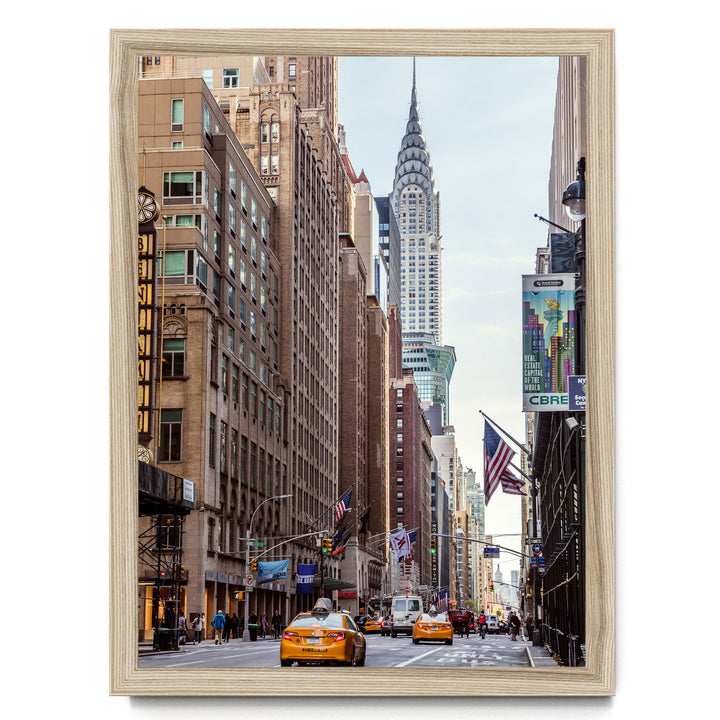 a busy city street with tall buildings, including the iconic New York City skyline, including the distinctive spire of the Chrysler Building.