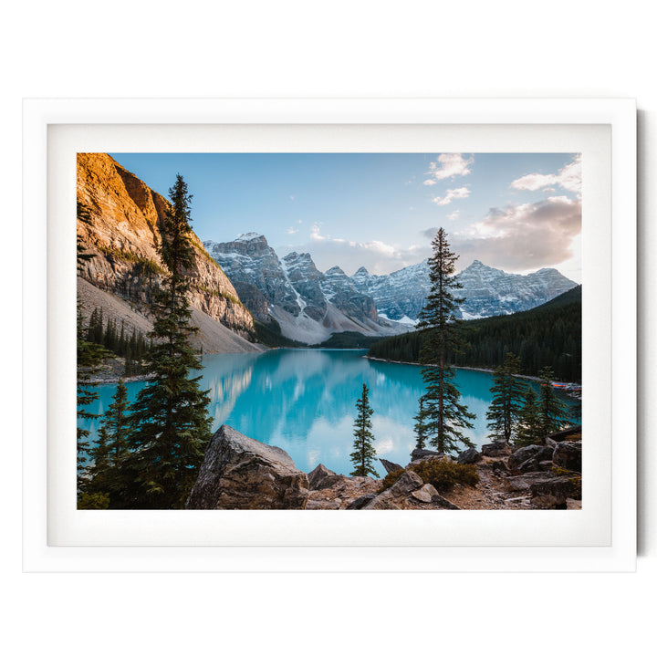 A breathtaking view of a serene mountain lake surrounded by towering peaks and lush forests, with a clear blue sky overhead.
