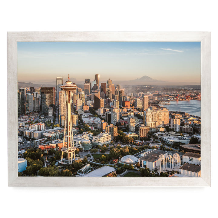 a cityscape with a tall tower, likely a landmark, surrounded by a variety of buildings and skyscrapers. The city appears to be at sunset, with the warm, golden light illuminating the scene.