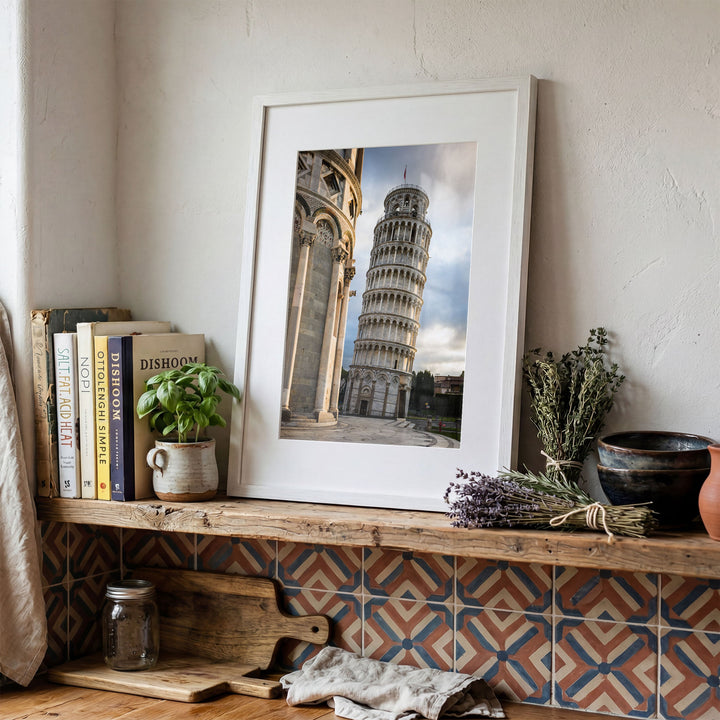 Leaning Tower of Pisa print in a white frame on a rustic wooden shelf