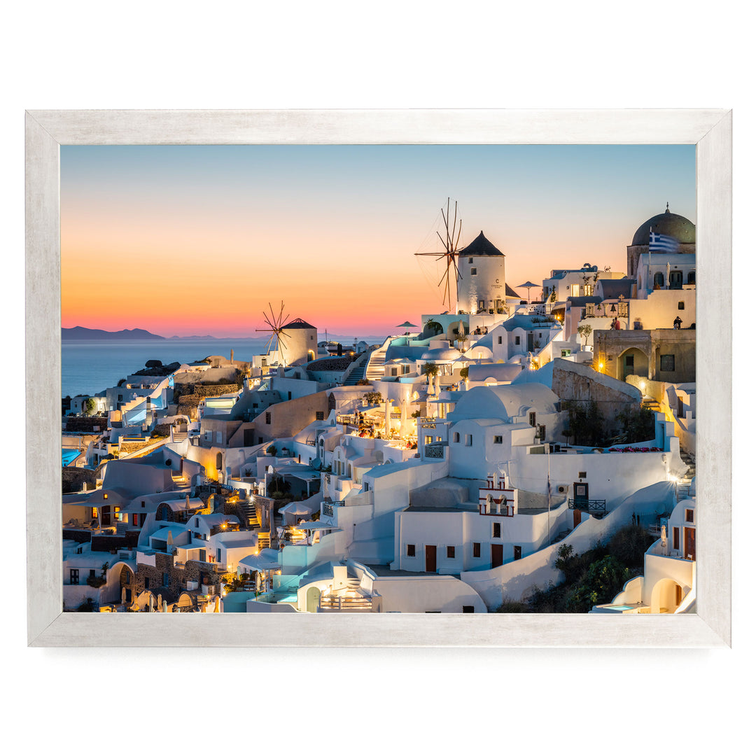 a picturesque coastal town with white buildings and windmills, set against a stunning sunset sky.