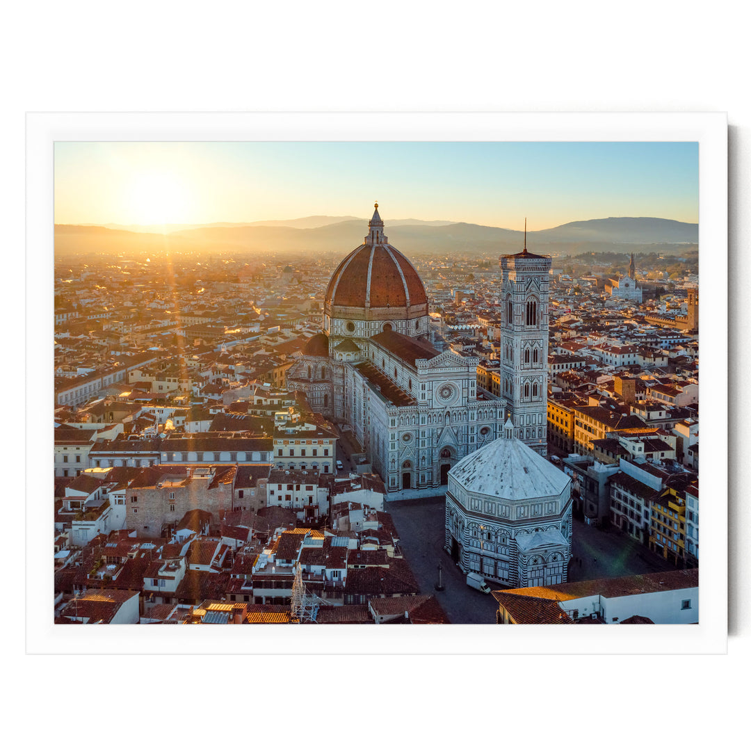 a cityscape with a large dome-shaped building, possibly a church or cathedral, surrounded by smaller buildings and structures. The sun is setting, casting a warm glow over the scene and creating a picturesque view of the city.