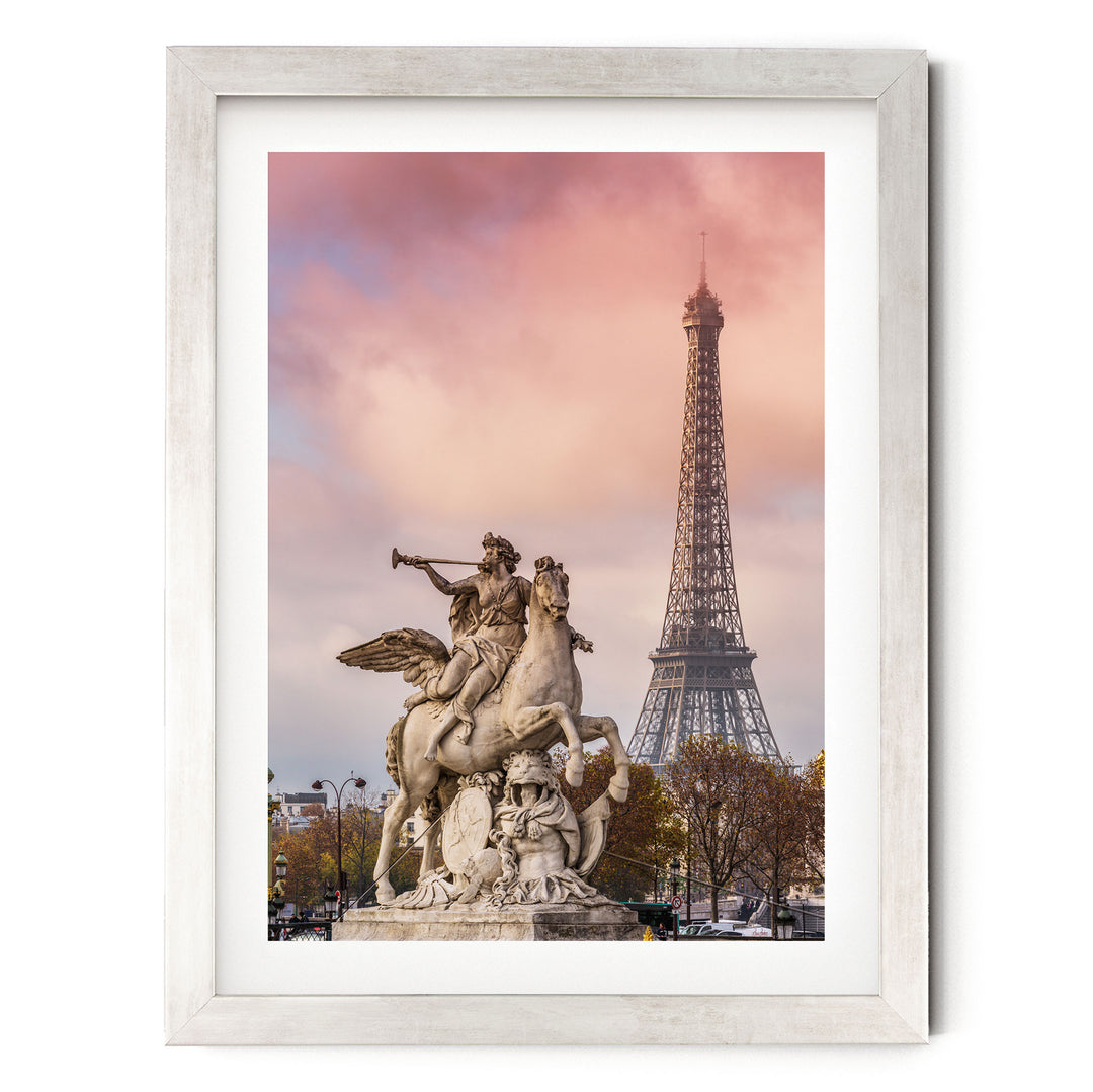 a large stone statue of a winged horseman with a trumpet, standing in front of the Eiffel Tower in Paris, France.