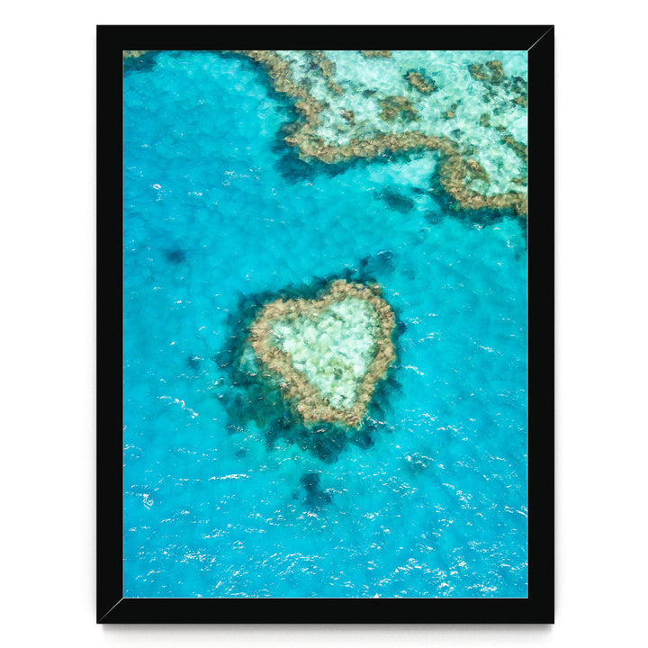 a heart-shaped coral reef in the center of the frame, surrounded by the vibrant blue ocean water.