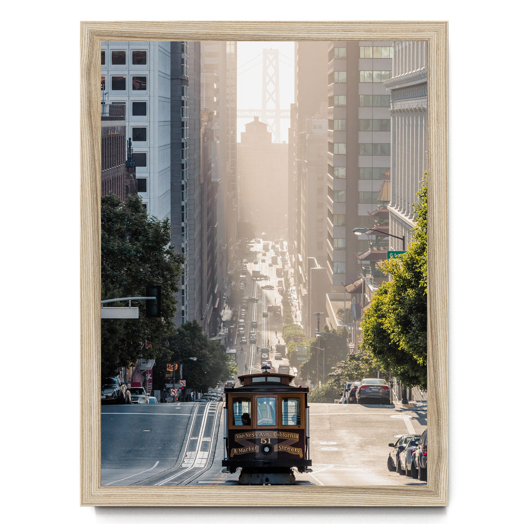 A trolley car travels down a busy street in San Francisco, surrounded by tall buildings and lush green trees.