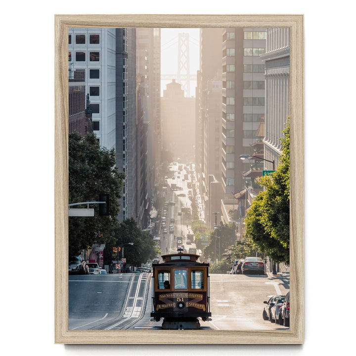 A trolley car travels down a busy street in San Francisco, surrounded by tall buildings and lush green trees.