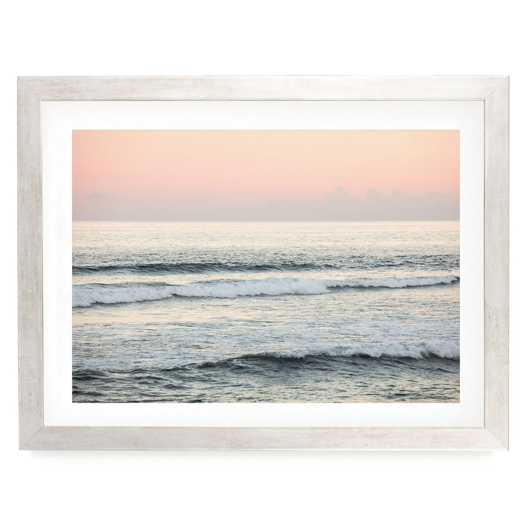A serene ocean scene with waves gently lapping against the shore, framed in a white wooden frame.