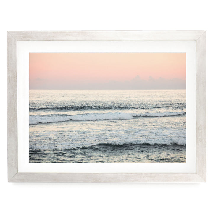 A serene ocean scene with waves gently lapping against the shore, framed in a white wooden frame.