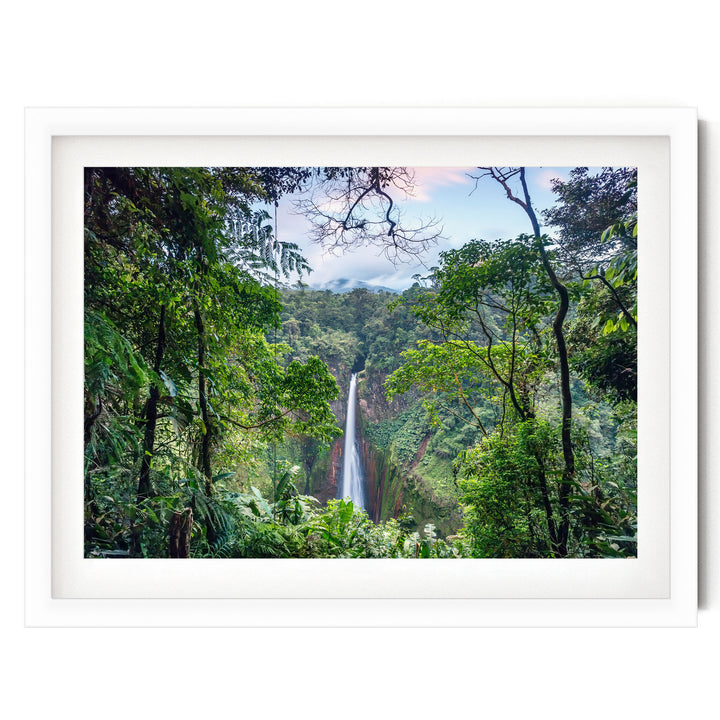 A lush, verdant forest with a towering waterfall cascading down the rocky cliff face, framed within a white border.