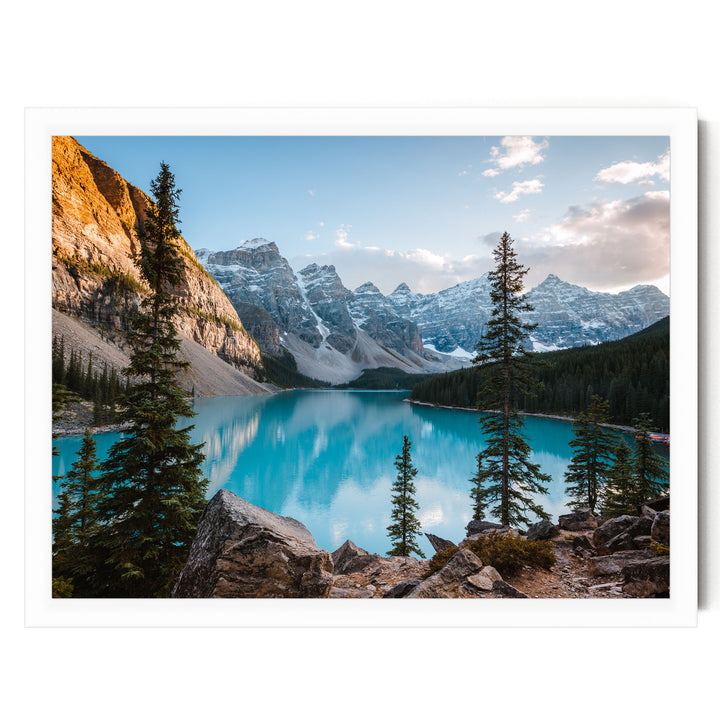 A breathtaking view of a serene mountain lake surrounded by snow-capped peaks and lush green forests. The deep blue lake reflects the clear sky, creating a stunning natural landscape.