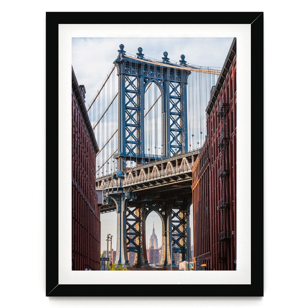 a large suspension bridge with multiple towers and cables, spanning across a street with buildings on either side.