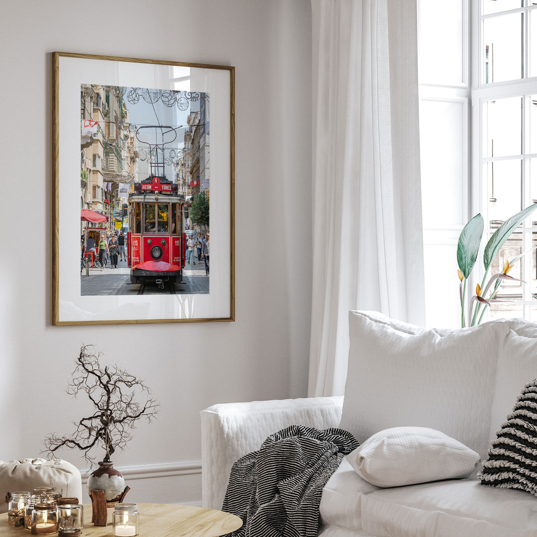 a framed photograph of a red trolley car in Istanbul, Turkey, hanging on a white wall above a white couch in a living room.
