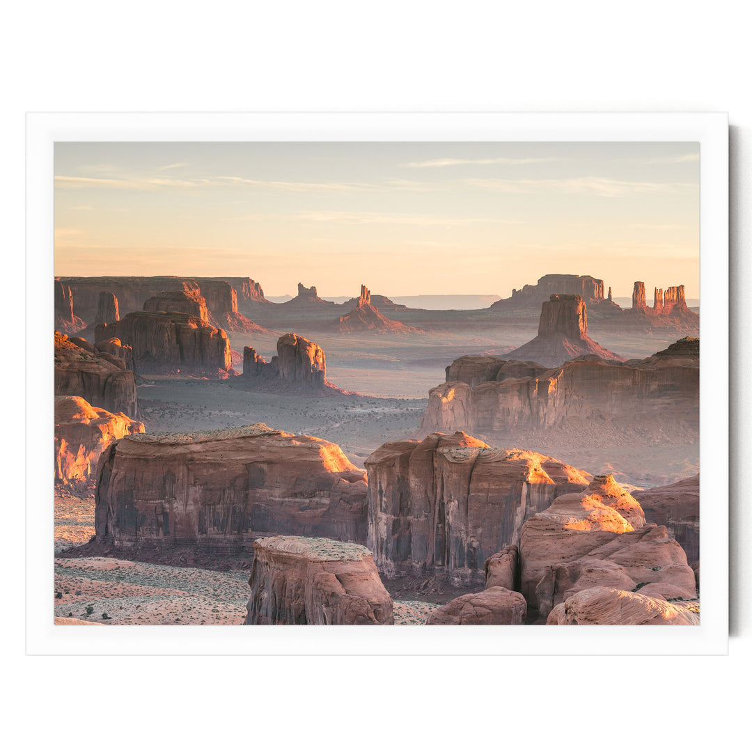 a breathtaking view of the desert landscape, showcasing towering rock formations and cliffs bathed in the warm glow of the setting sun.