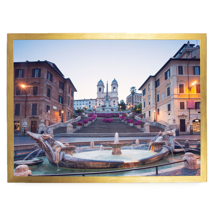 a picturesque scene of a fountain situated in a city square, with a church steeple visible in the background.