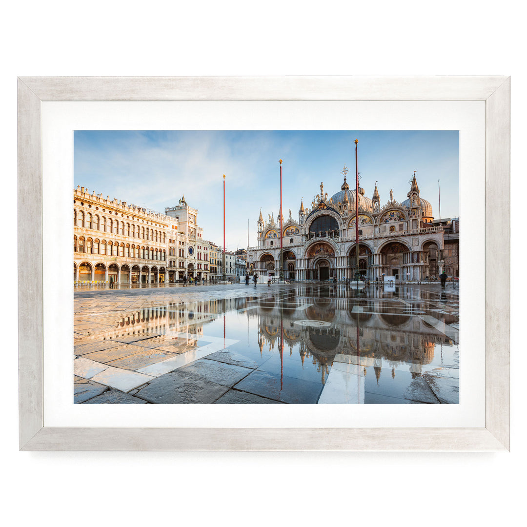 a large, ornate building with a domed roof and multiple arches, situated in a square with a fountain in the foreground. The building is reflected in the water, creating a symmetrical and visually striking scene.