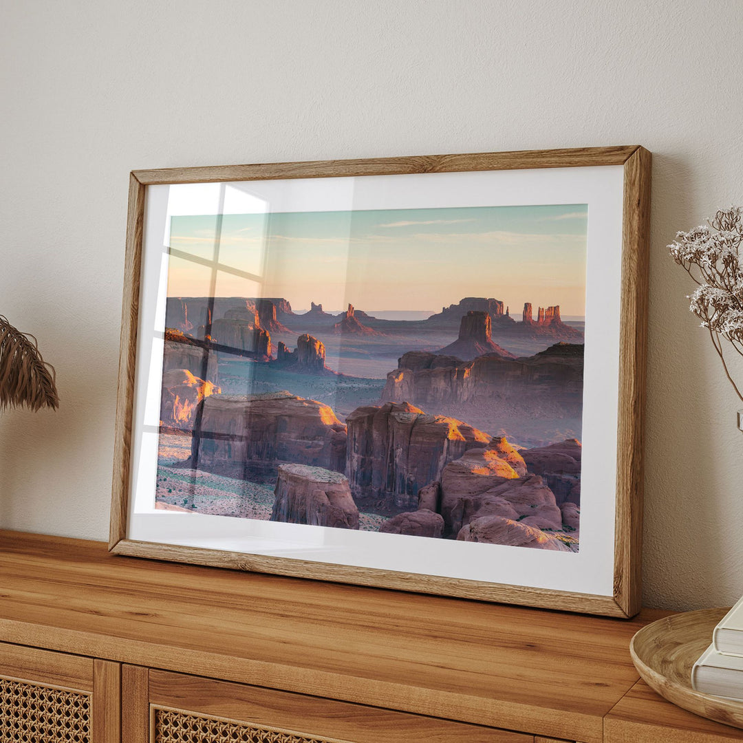 a framed photograph of a scenic desert landscape with towering rock formations and a warm, golden sunset.