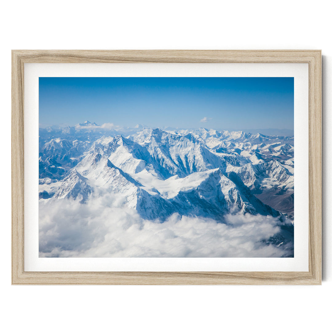 a breathtaking view of snow-capped mountains rising above a vast expanse of clouds, creating a stunning natural landscape.
