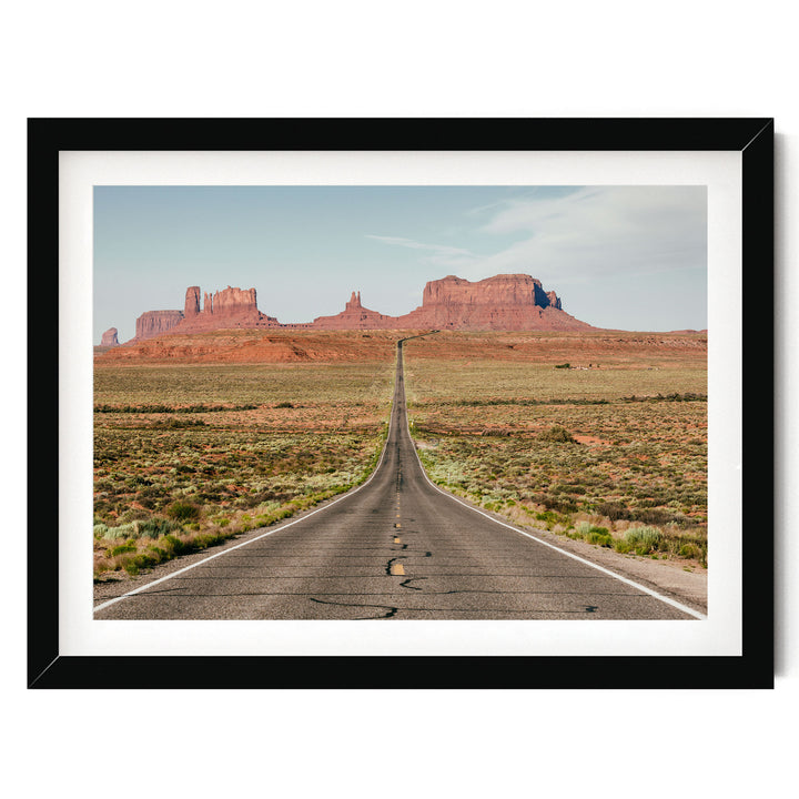 A long, straight road stretches into the distance, leading towards a majestic mountain range in the background.