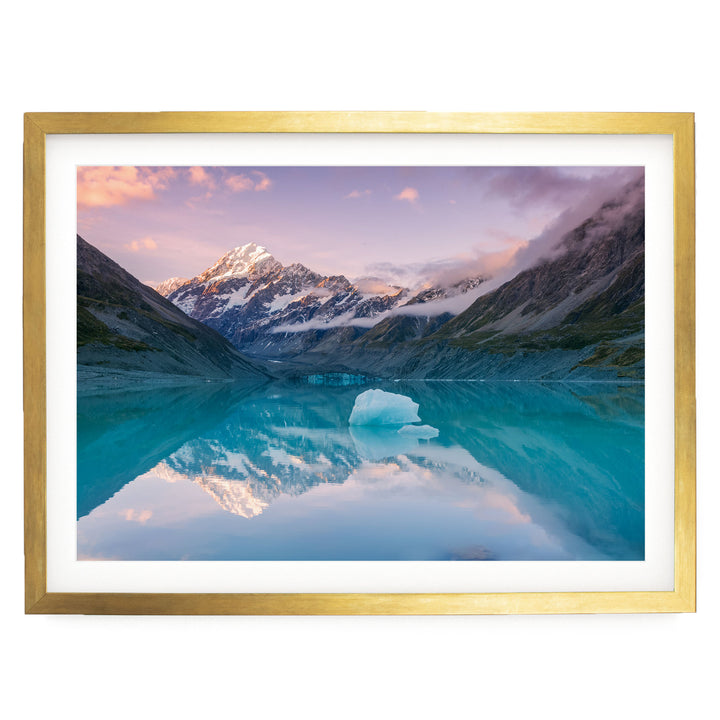 a serene mountain landscape with a large ice formation in the foreground, its reflection mirrored perfectly in the still waters of a lake or pond. The sky above is a beautiful gradient of pink and purple hues, creating a stunning backdrop for the scene. The overall composition is balanced and harmonious, with the natural elements of the landscape and the ice formation creating a sense of tranquility and peace.