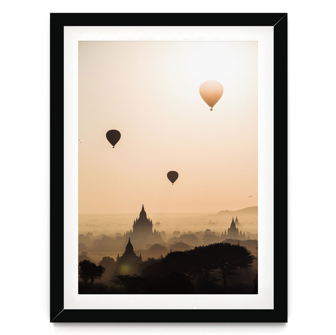 three hot air balloons floating in the sky above a cityscape with silhouetted buildings.