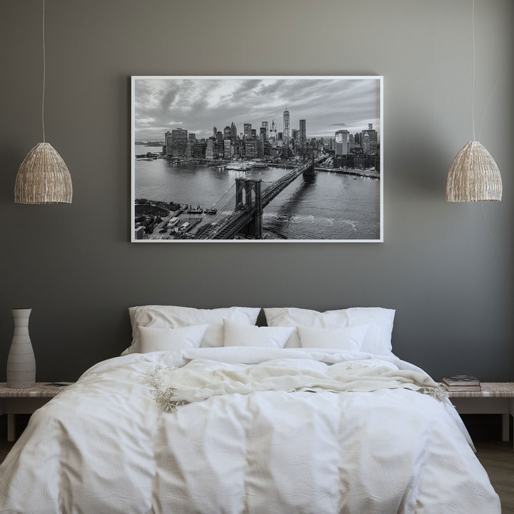 a bedroom with a large black and white photograph of the Brooklyn Bridge hanging on the wall above a bed with white bedding.