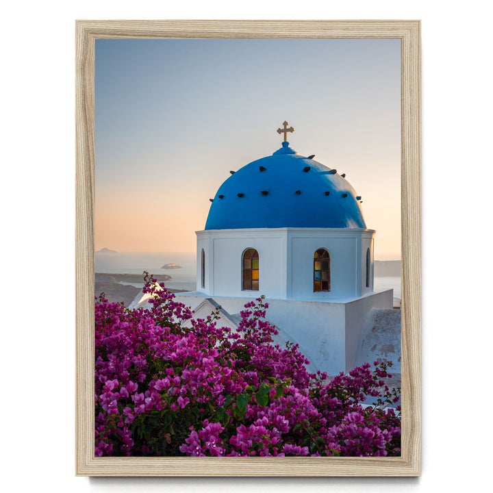 a blue domed church with a cross on top, surrounded by a vibrant display of purple flowers.