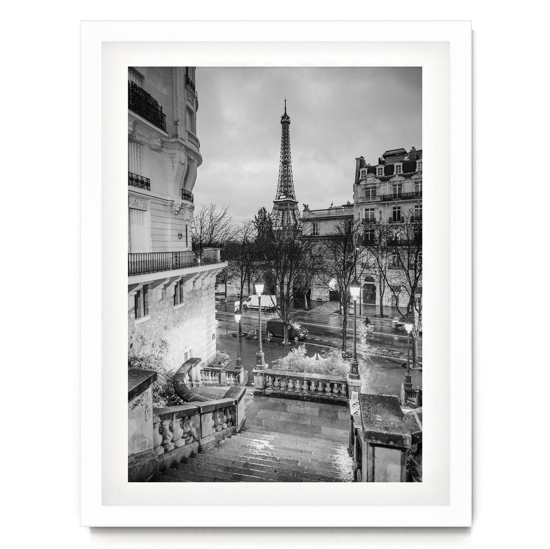 A black and white photograph of the Eiffel Tower in Paris, France, with the surrounding buildings and streets visible.
