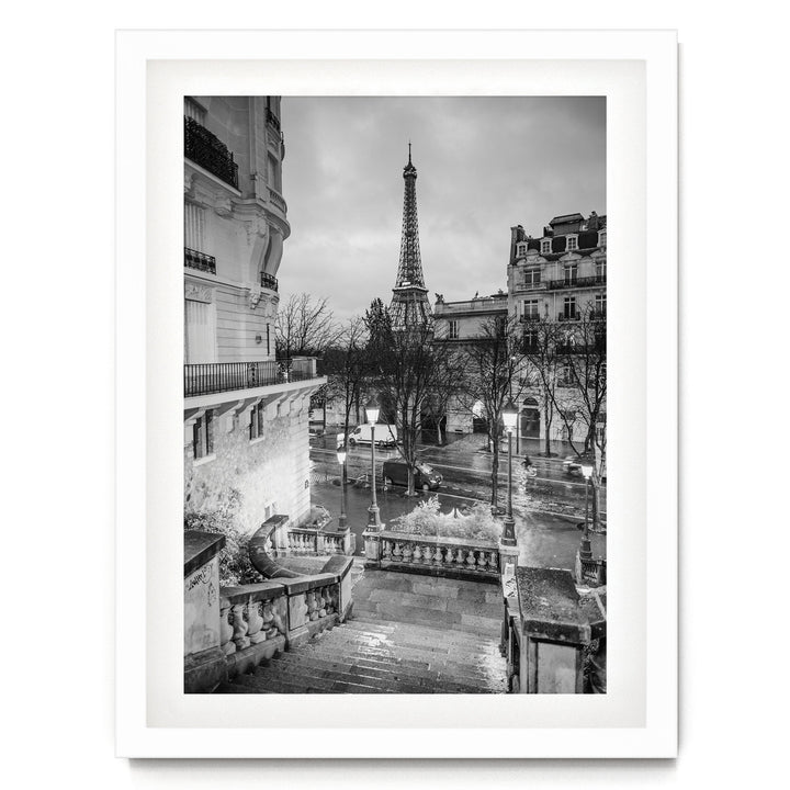 A black and white photograph of the Eiffel Tower in Paris, France, with the surrounding buildings and streets visible.