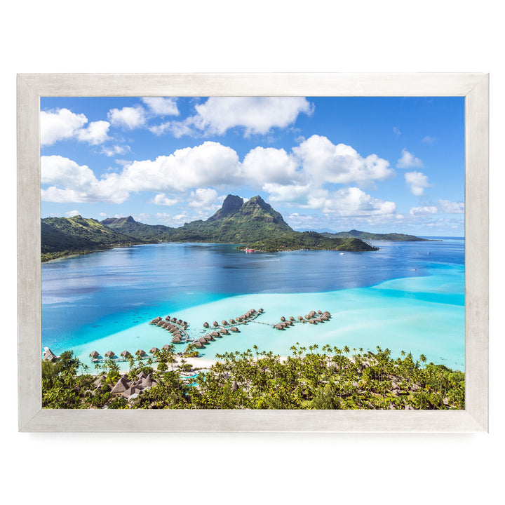 a tropical island with crystal clear turquoise waters, lush green vegetation, and a mountainous backdrop.