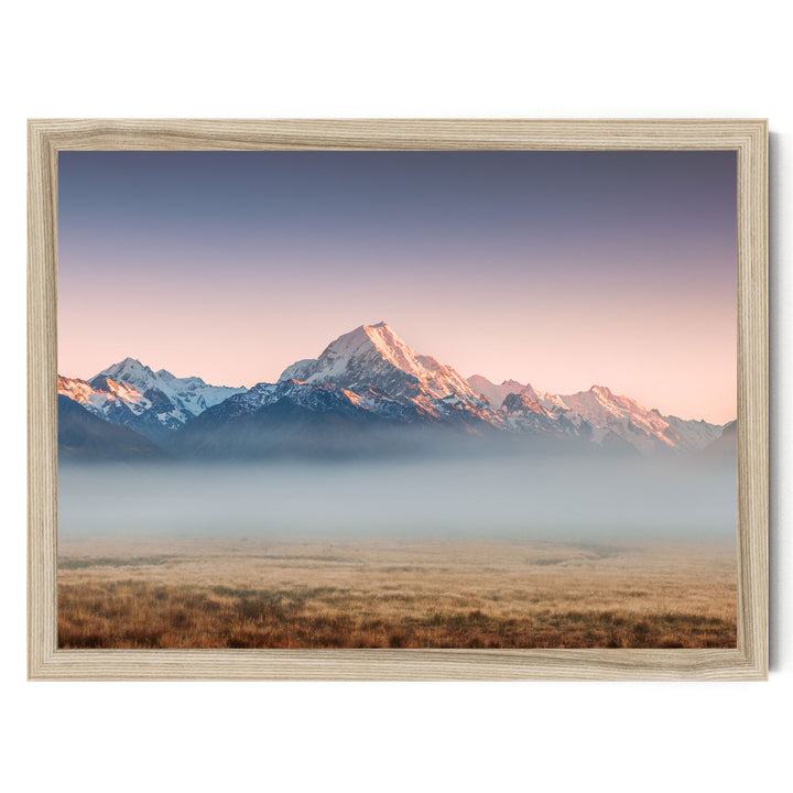 a breathtaking mountain range with snow-capped peaks against a vibrant sky, partially obscured by a hazy mist.