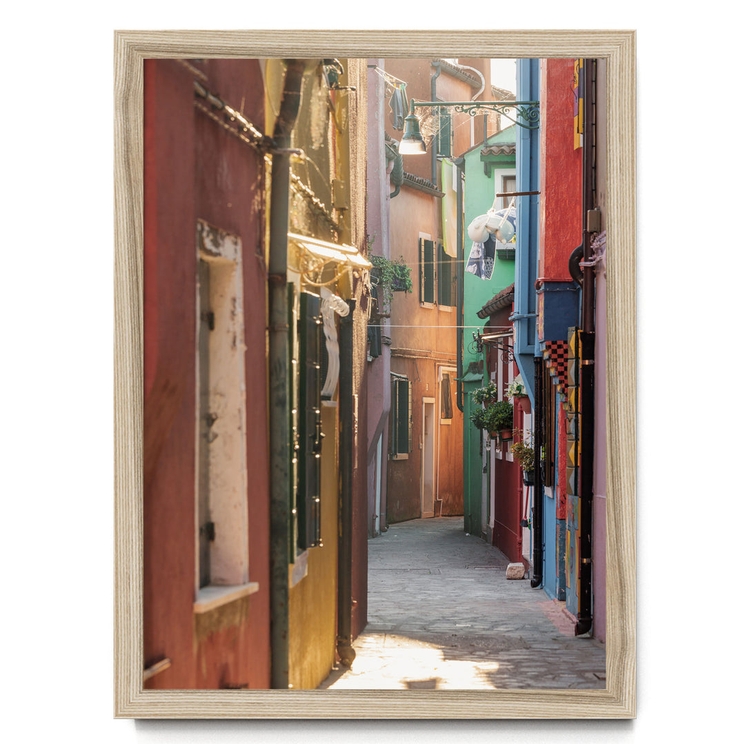 A narrow, colorful alleyway in a city, with buildings painted in various vibrant colors lining the sides. The sunlight filters through the buildings, creating a warm and inviting atmosphere.