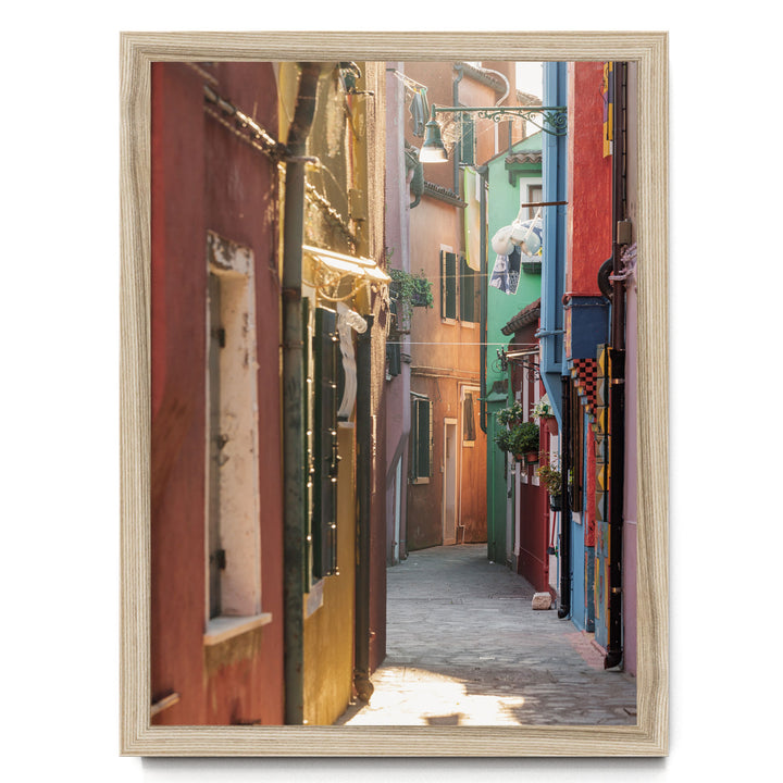 A narrow, colorful alleyway in a city, with buildings painted in various vibrant colors lining the sides. The sunlight filters through the buildings, creating a warm and inviting atmosphere.