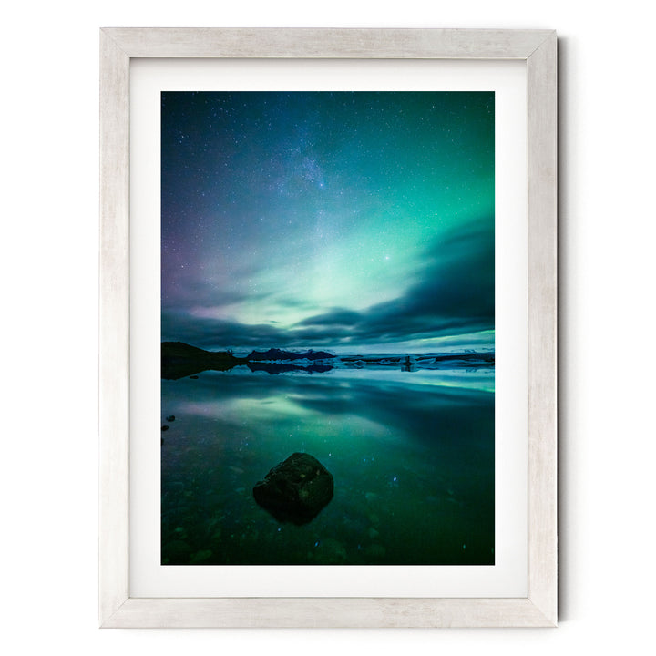 a serene night scene with a calm body of water reflecting the vibrant colors of the night sky, including the mesmerizing northern lights.
