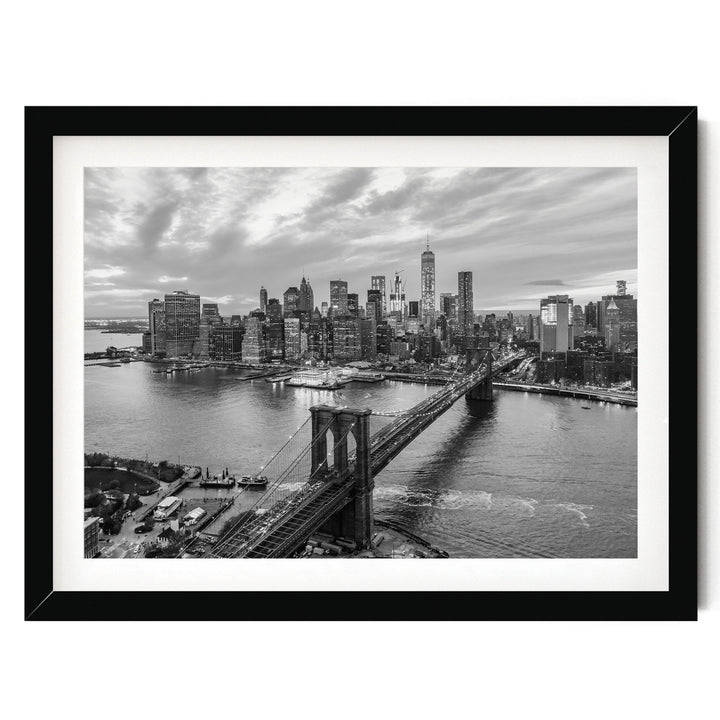A black and white photograph of the New York City skyline, featuring the Brooklyn Bridge and the surrounding cityscape.