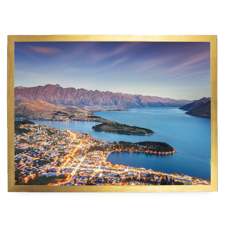 a picturesque city nestled at the foot of a mountain range, with a stunning view of the city lights reflected in the calm waters of the lake or river.