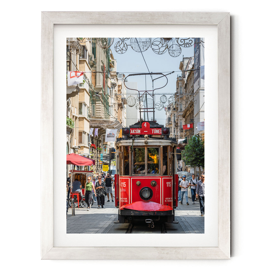 A red trolley car is traveling down a busy street in Istanbul, Turkey, surrounded by pedestrians and other vehicles.