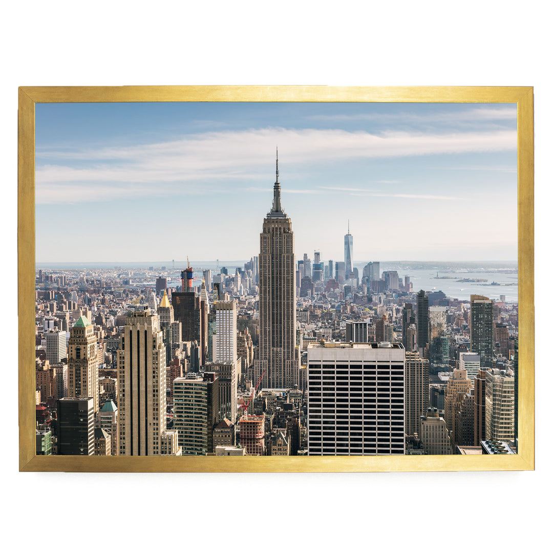 a panoramic view of the New York City skyline, with the iconic Empire State Building and other skyscrapers visible against a clear blue sky.