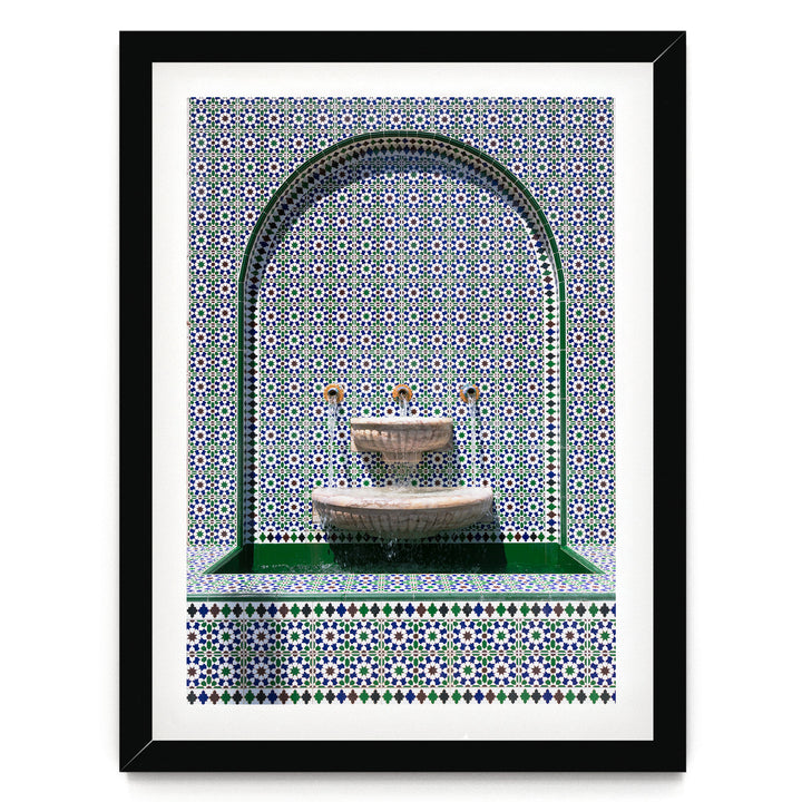 a decorative fountain with a green border and a tiled wall with a pattern of blue and white tiles.