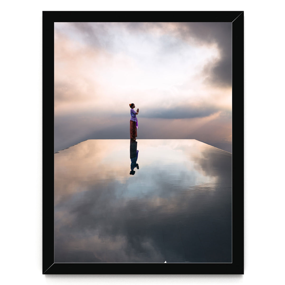 A person stands on a reflective surface, gazing out at the horizon where the sky meets the clouds, creating a serene and contemplative scene.