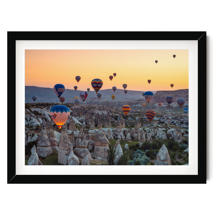 a breathtaking scene of hot air balloons floating over a mountainous landscape at sunset.