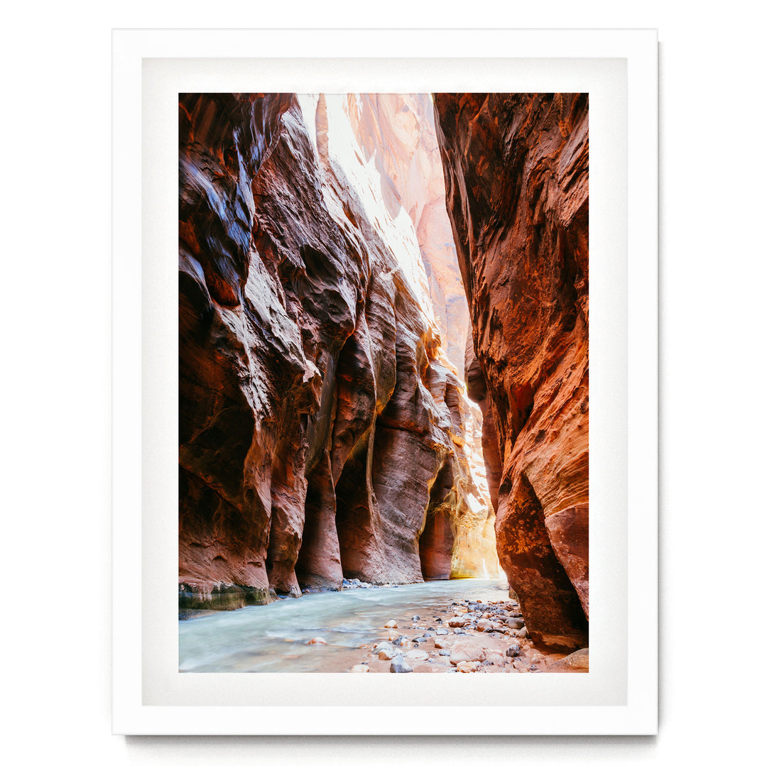 A framed image depicting a narrow, winding river flowing through a canyon with towering red rock walls on either side.