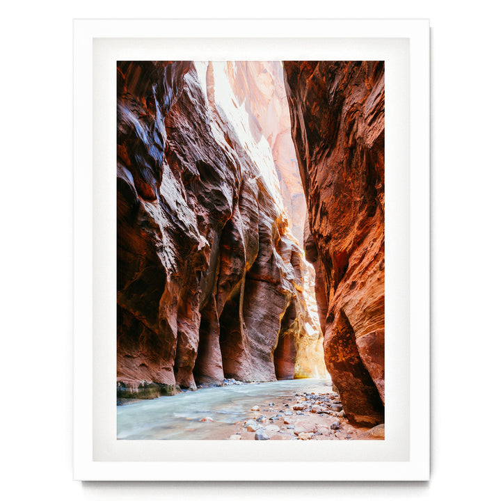 A framed image depicting a narrow, winding river flowing through a canyon with towering red rock walls on either side.
