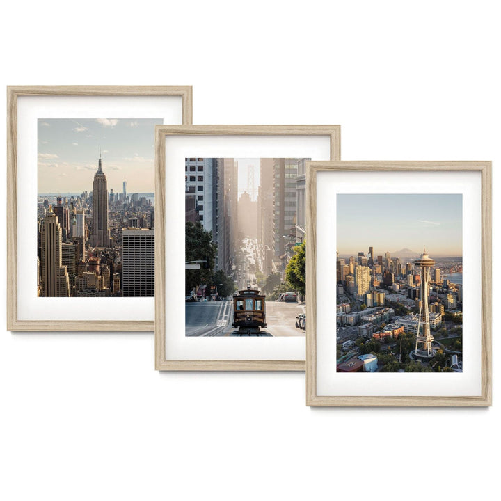 three framed photographs of different cityscapes, including the iconic Empire State Building, a trolley car, and a view of the Seattle Space Needle.