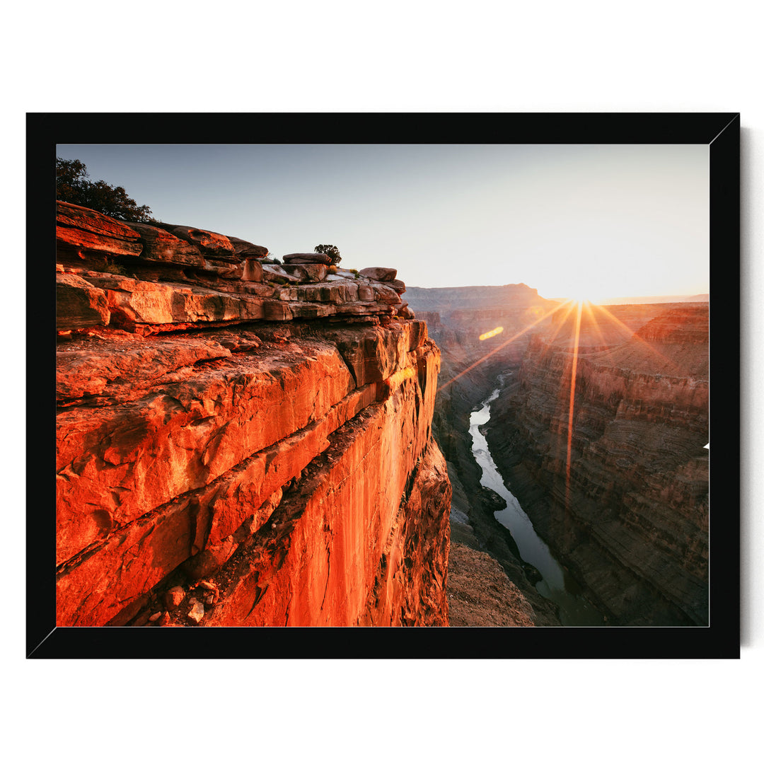 A breathtaking view of a canyon at sunset, with the sun's rays shining down on the rugged, rocky cliffs and the winding river below.