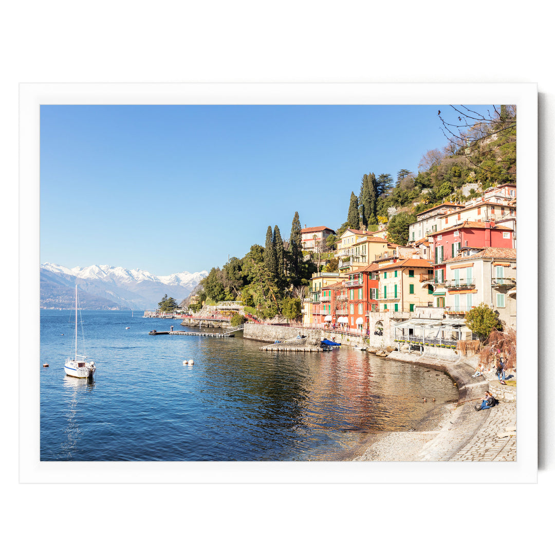 A picturesque coastal town with colorful buildings, a small boat on the water, and snow-capped mountains in the background.