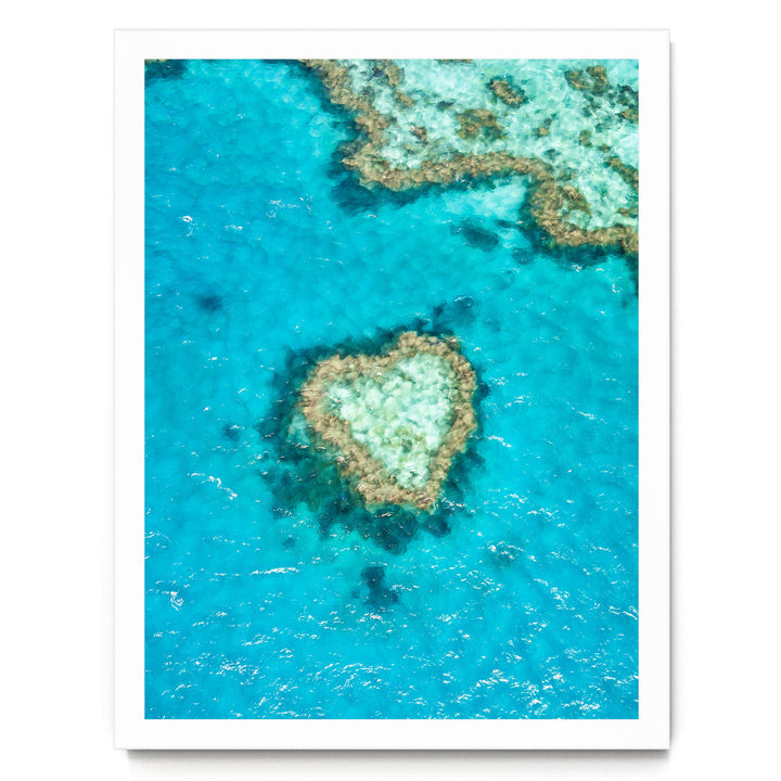 An aerial view of a vibrant coral reef, with a heart-shaped coral formation in the center surrounded by the blue-green waters.