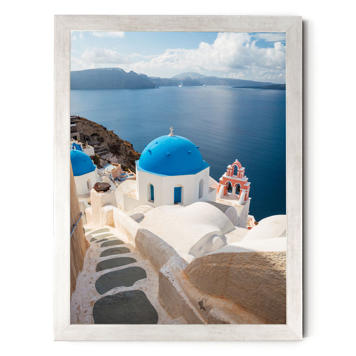 a picturesque view of a Greek island, with white buildings featuring blue domes and orange roofs, overlooking the deep blue sea.