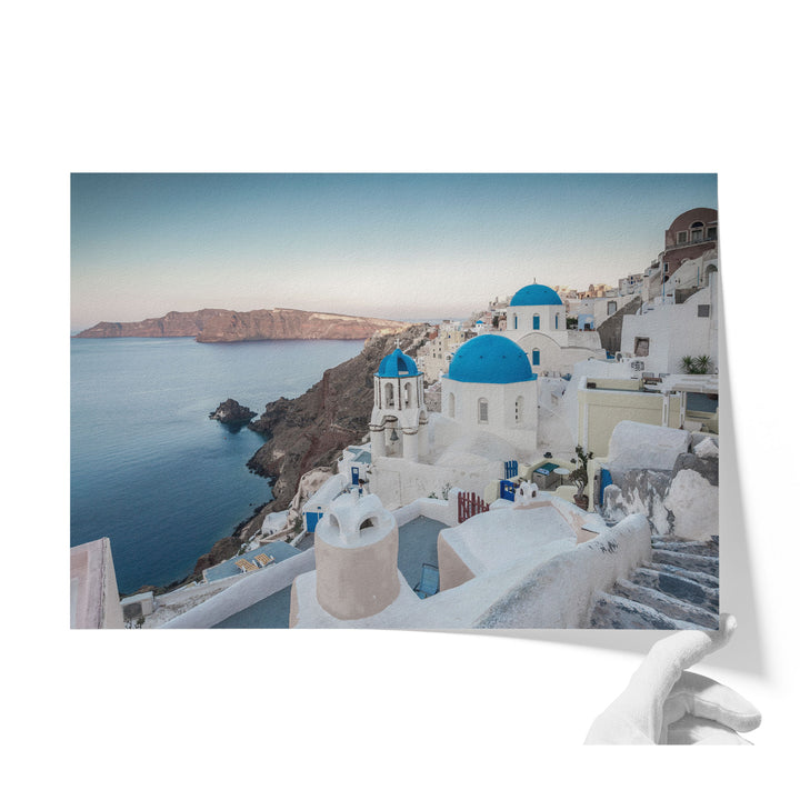 a picturesque coastal town with white buildings and blue domes overlooking the ocean.