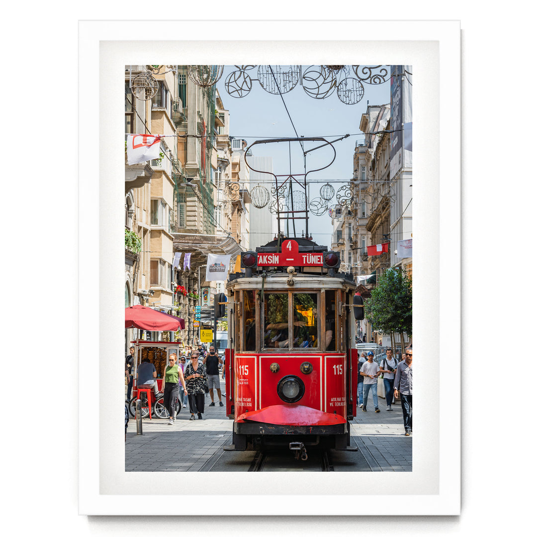 A red trolley car is traveling down a busy street in Istanbul, Turkey, surrounded by pedestrians and buildings.