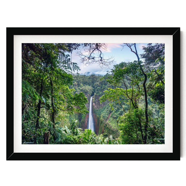 A lush, verdant forest with a towering waterfall cascading down the rocky cliff face, framed in a black border.
